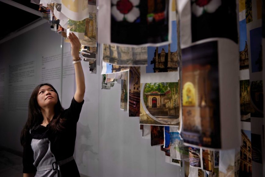 Ina Lao Man Si reaching up to one of the canvas pieces in her 'Coexistence' exhibition