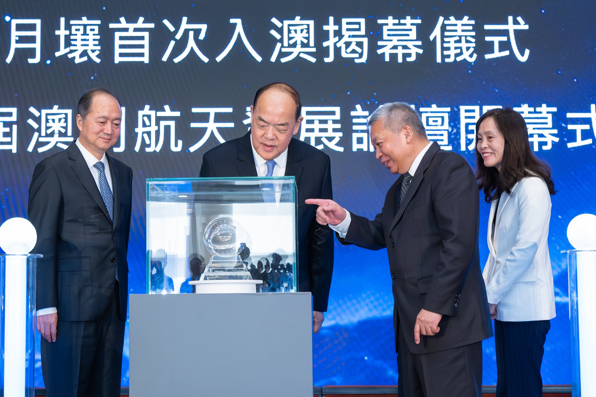Ho Iat Seng (2nd L), chief executive of Macao, Zheng Xincong (1st L), director of the Liaison Office of the Central People's Government in Macao, and Zhang Kejian (2nd R), head of the China National Space Administration, look at the lunar soil during the opening ceremony of an exhibition of China's achievements on space exploration and navigation