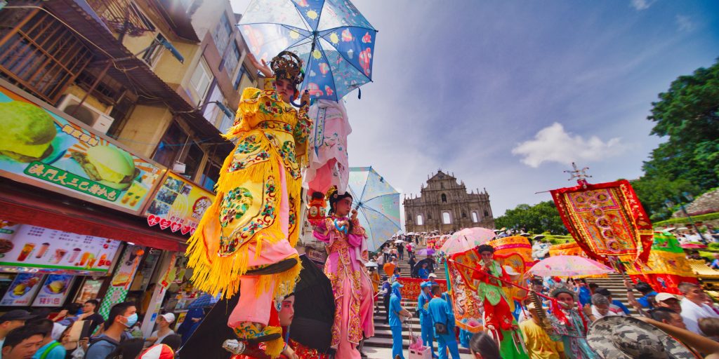 Children dressed as deities watch over on excited crowds along the parade route