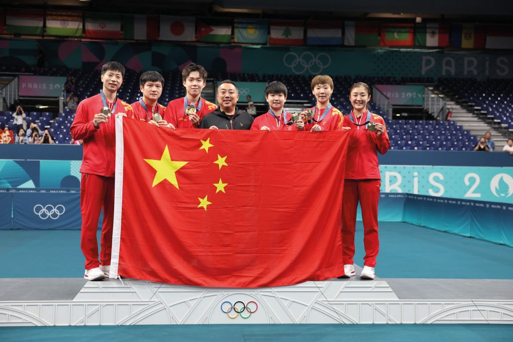 (Left to right) Table tennis player Ma Long (left) and diving athletes Quan Hongchan and Chen Yuxi pose for photographs with their welcome bouquets; Chairman of the Chinese Table Tennis Association Liu Guoliang (centre) poses with China’s winning table tennis team at the Paris Olympics