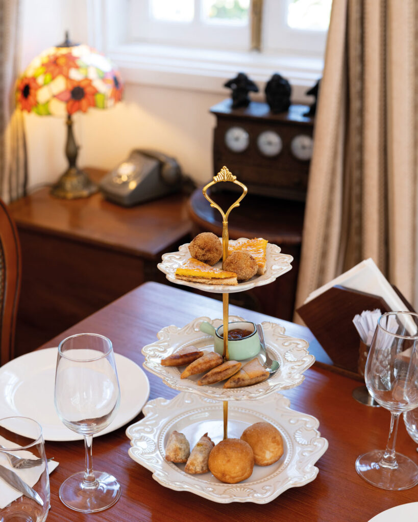 An appetizer tower featuring chilicote (turmeric dumplings) and tosta de queijo (cheese toast), along with other traditional bites