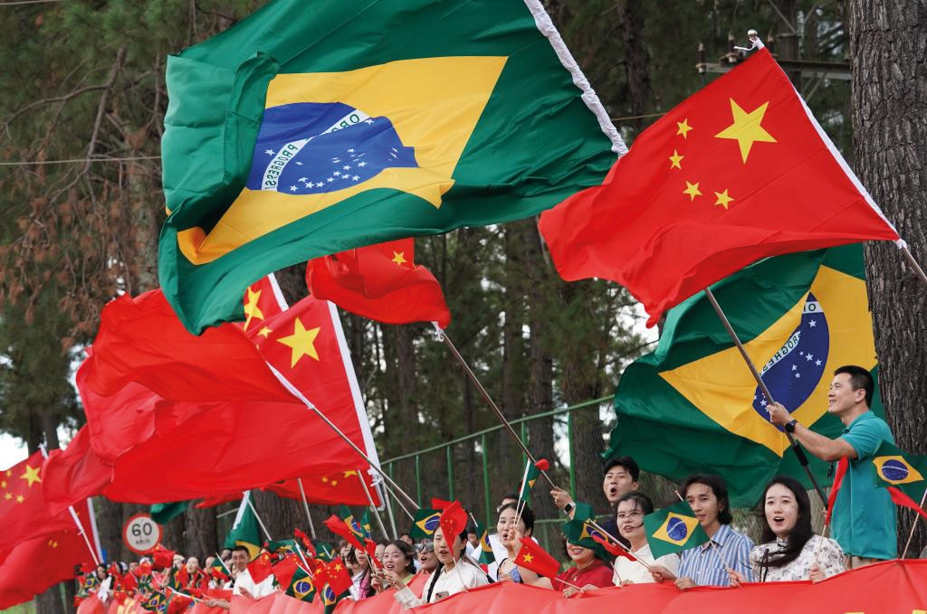 Crowds gather on the roadside, waving both Chinese and Brazilian flags, to welcome President Xi Jinping