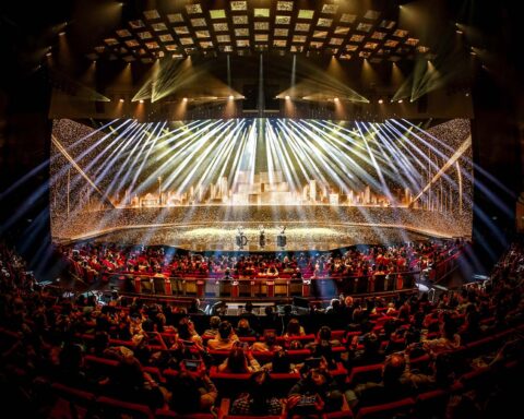 Golden balls cascade behind performers while high tech lasers dazzle the audience during Macau 2049’s inaugural show
