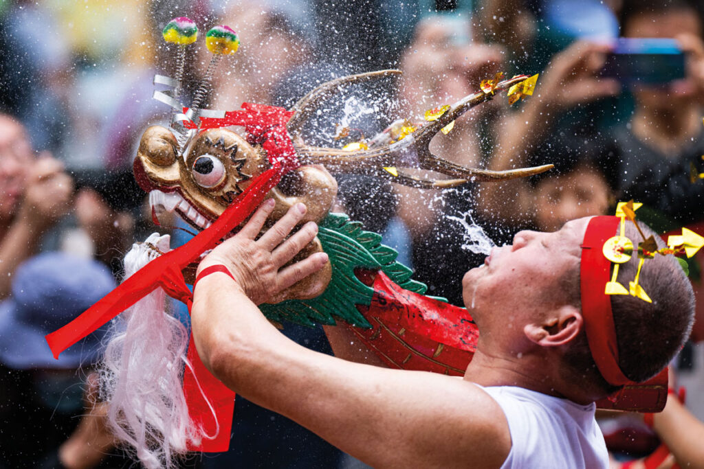 Participants in the Drunken Dragon Parade joyfully expel rice wine from their mouths, in part to appear more dragon-like